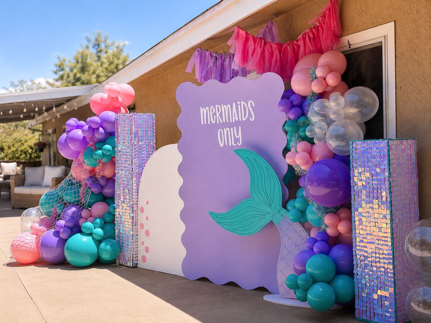 Mermaid themed party backdrop with purple and teal balloon garlands and shimmer panels