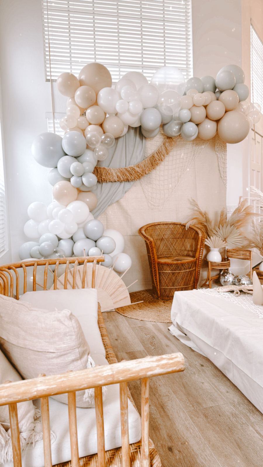 Neutral balloon garland styled over a wicker bassinet corner