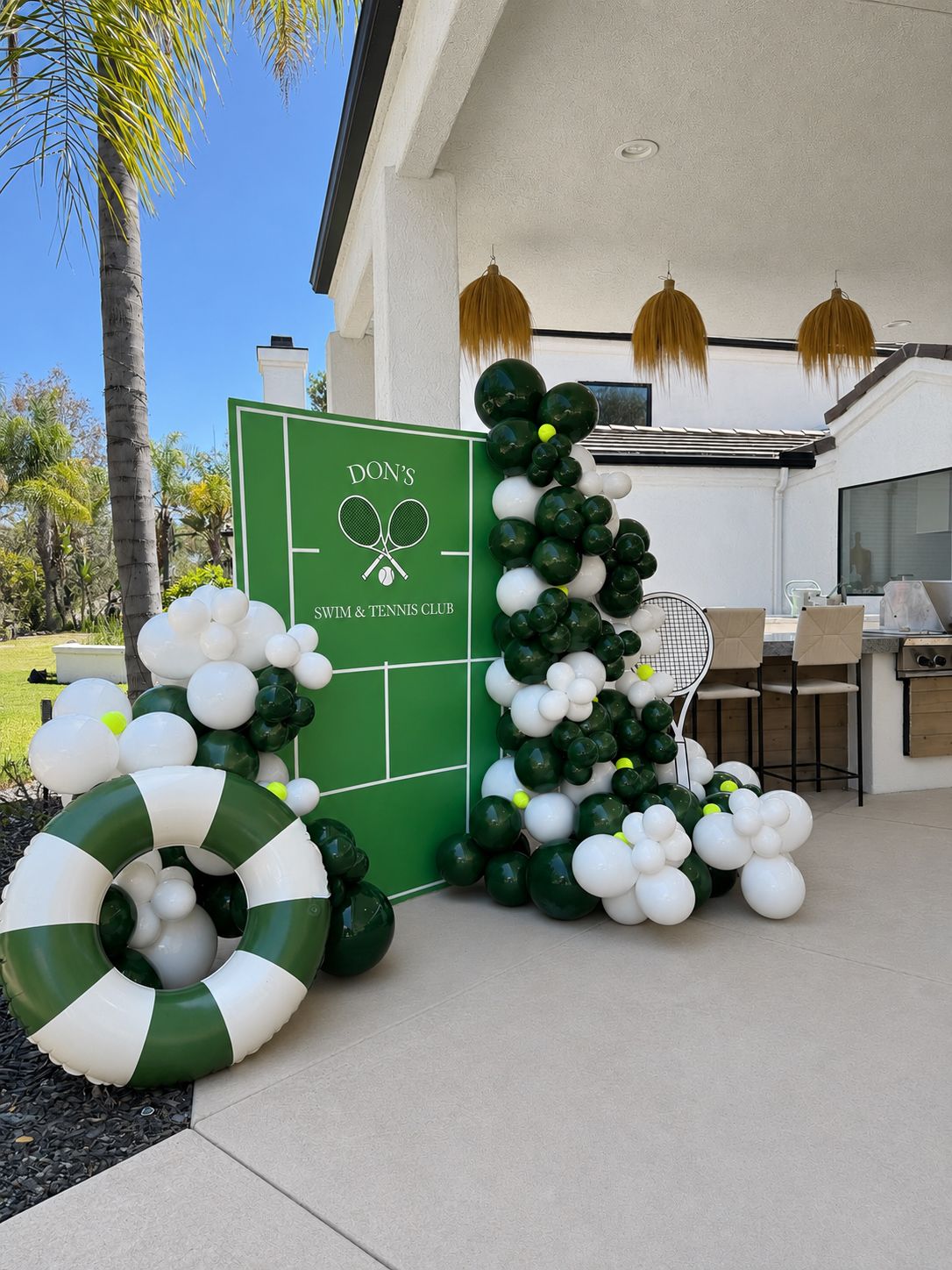 Tennis court backdrop with green and white balloon garland