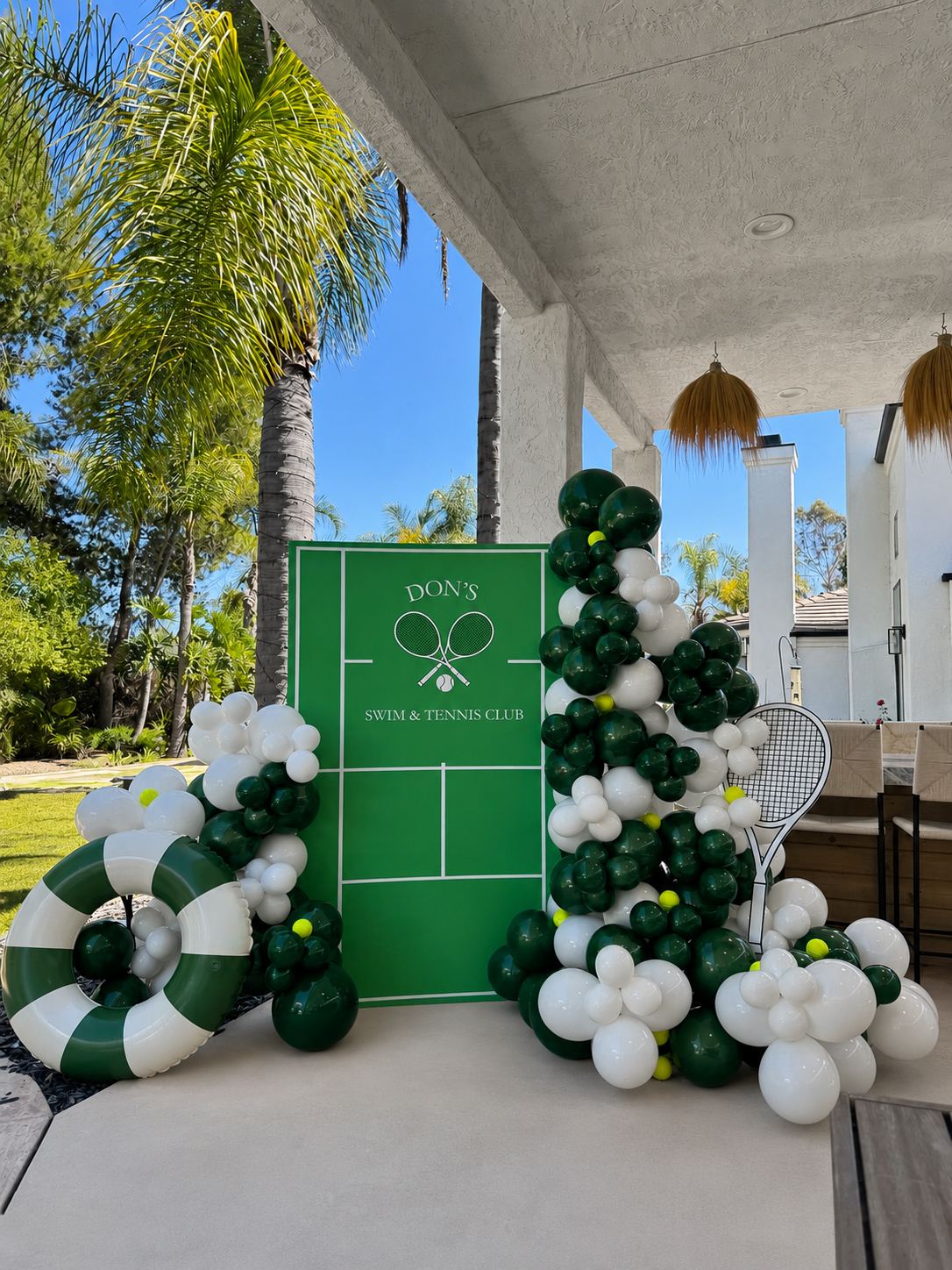 Tennis court backdrop with green and white balloons on a porch
