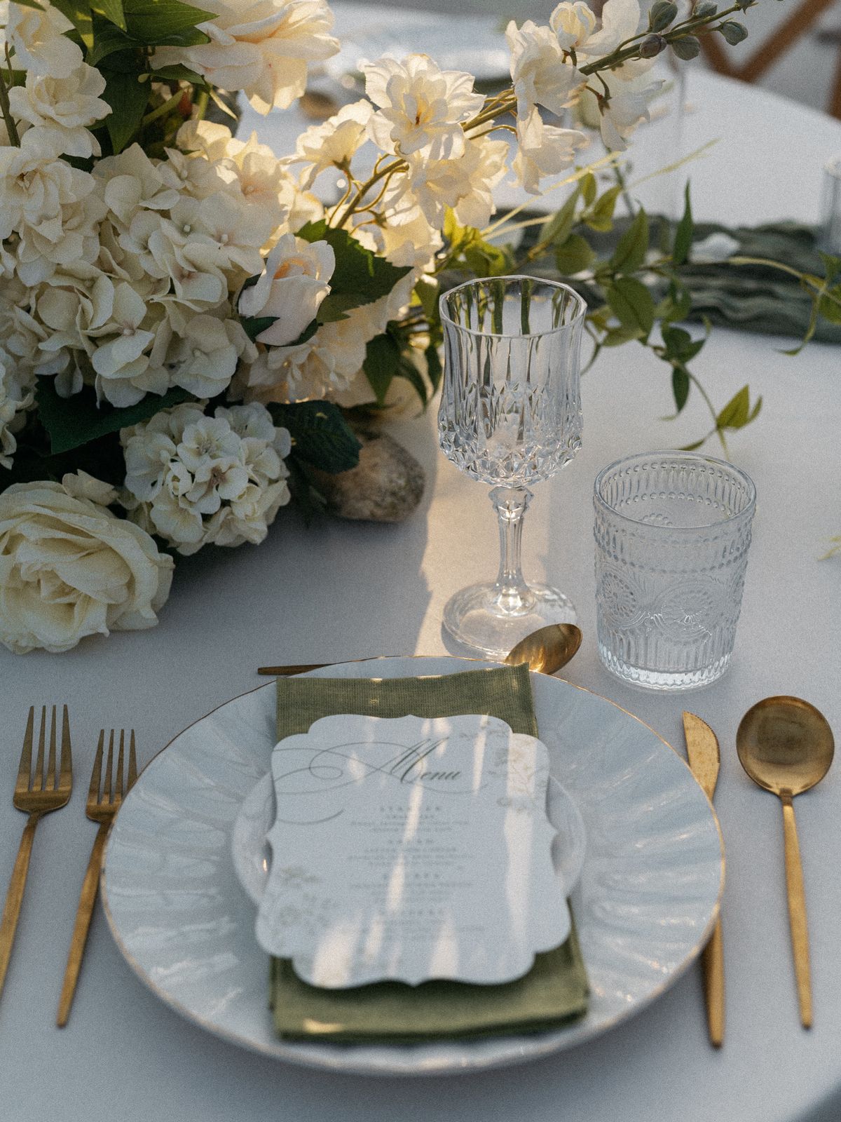 White and gold place setting with layered plates and gold flatware