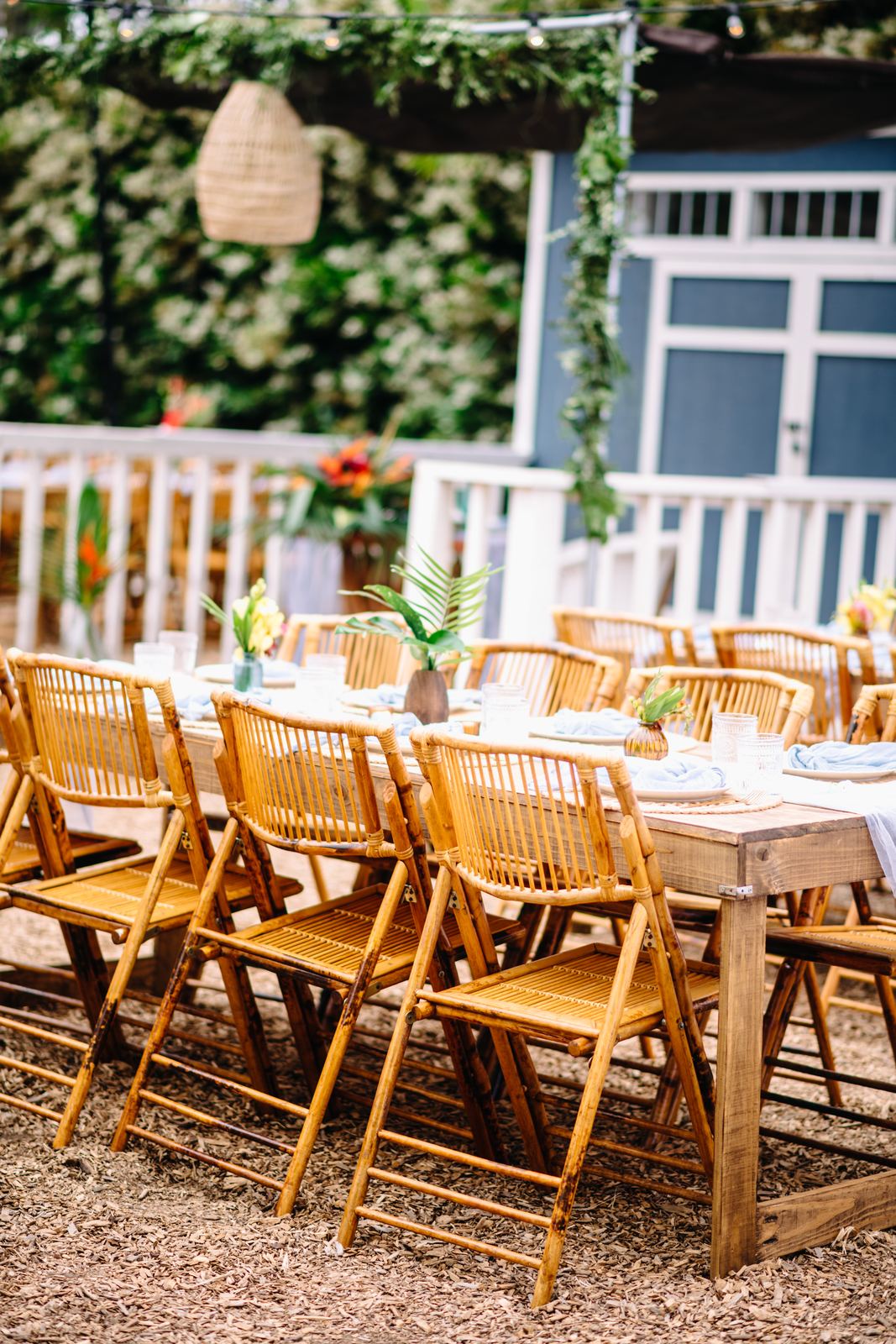 Wooden tables and chairs set for dinner under the trees