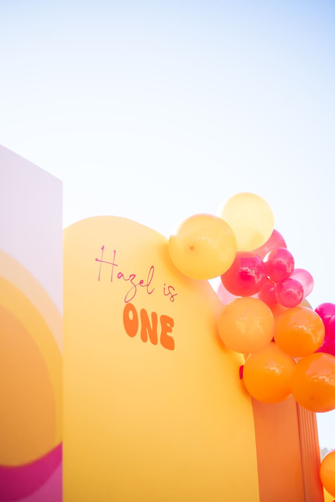Orange and pink first birthday backdrop with balloons