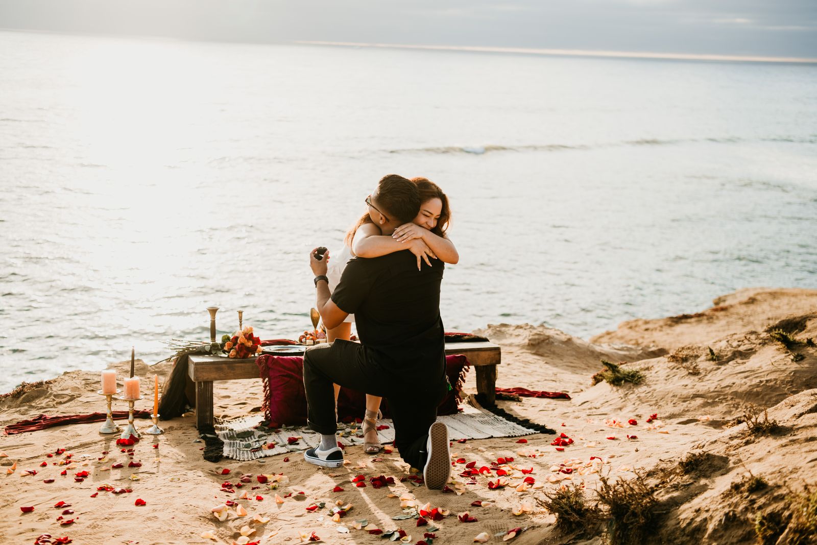 Beach proposal picnic with rose petals at sunset on the bluffs