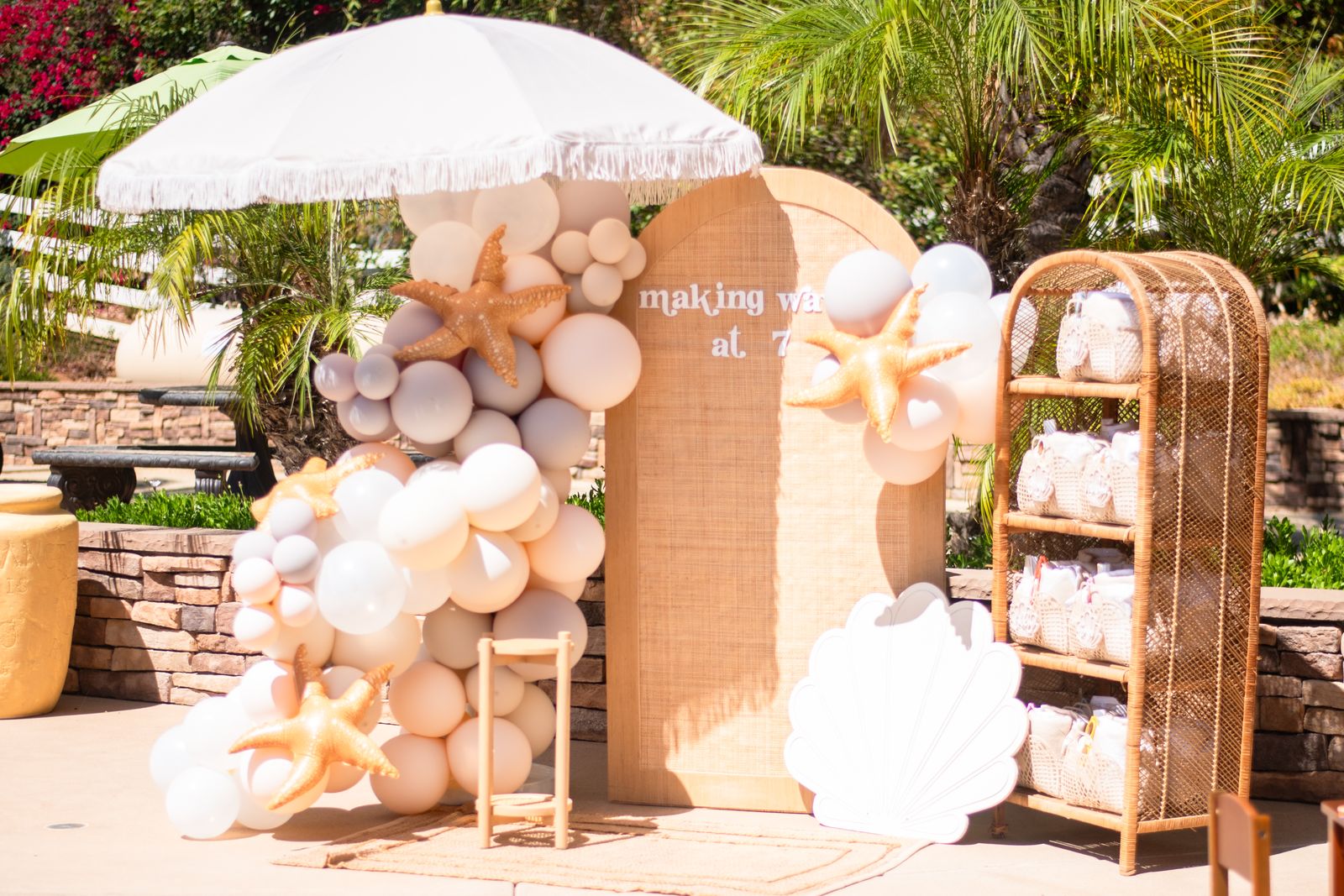 Boho beach lounge with fringe umbrellas, shelf displays and balloon garlands