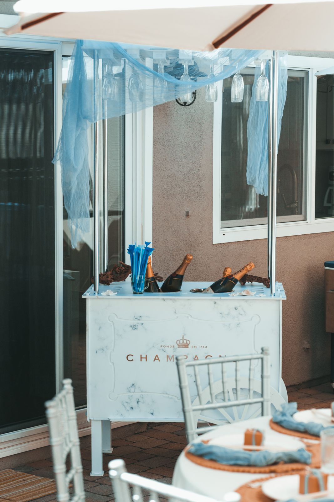 Coastal themed champagne cart with blue draping and netting