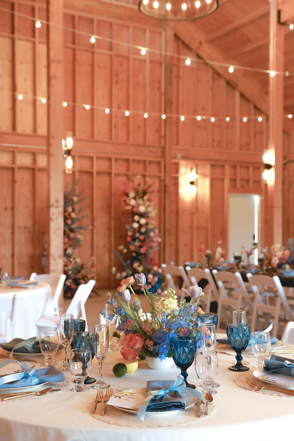 Barn reception tables with blue glassware and candles