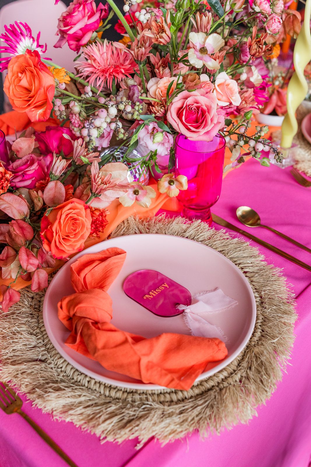 Hot pink and orange tablescape with fringe placemats and bold centerpieces