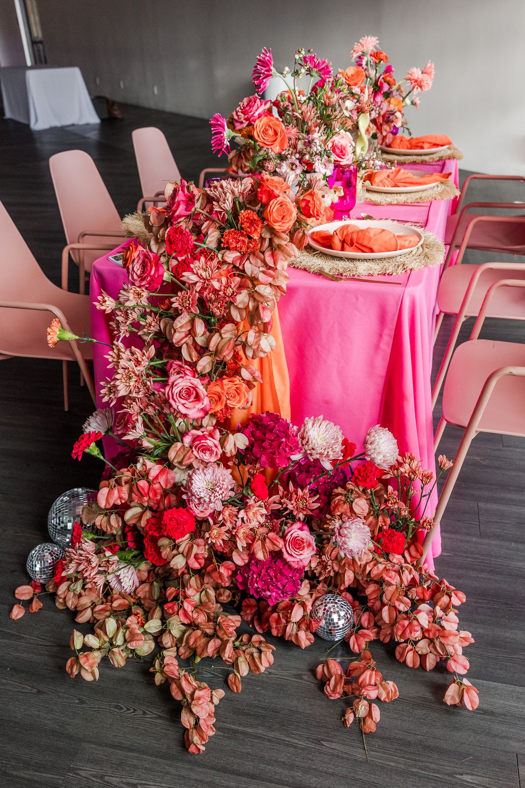 Long dining table covered in a full floral runner in pinks and corals