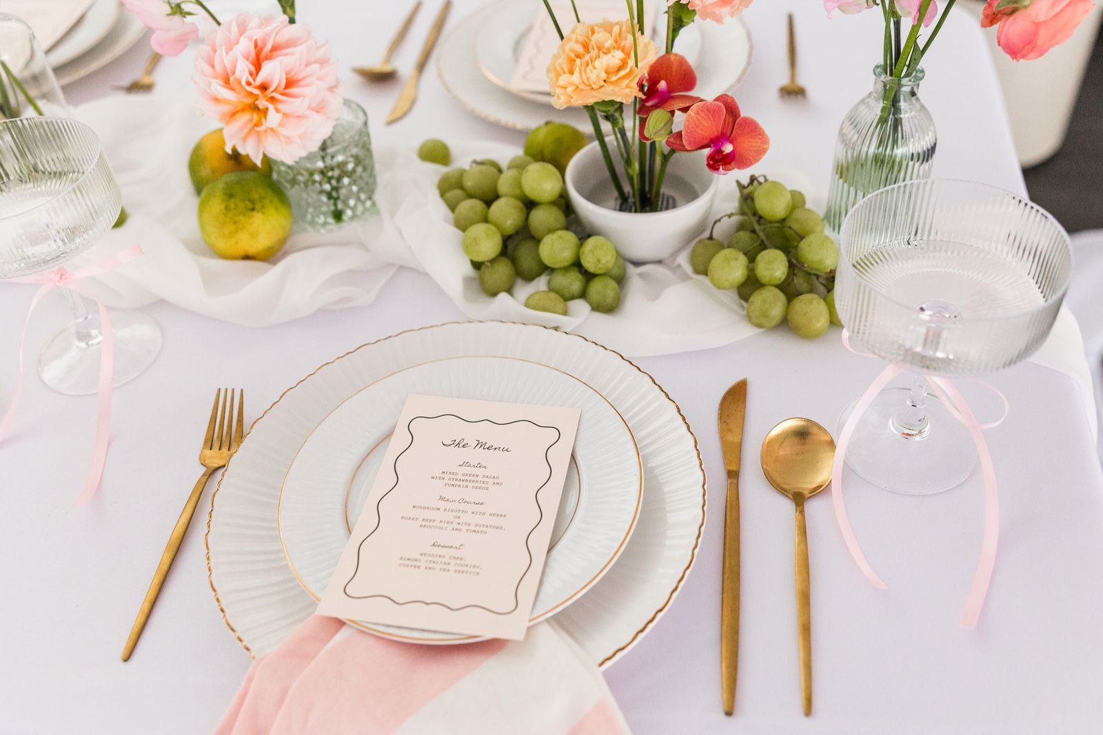Citrus themed place settings with grapes, wavy menus and gold flatware