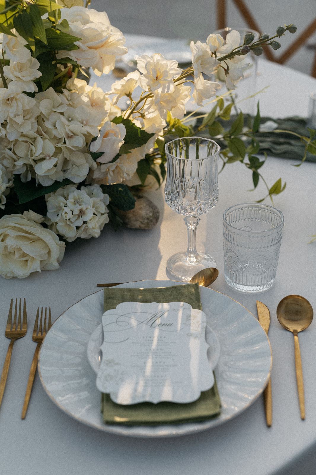 Scalloped plate setting with gold flatware and white florals
