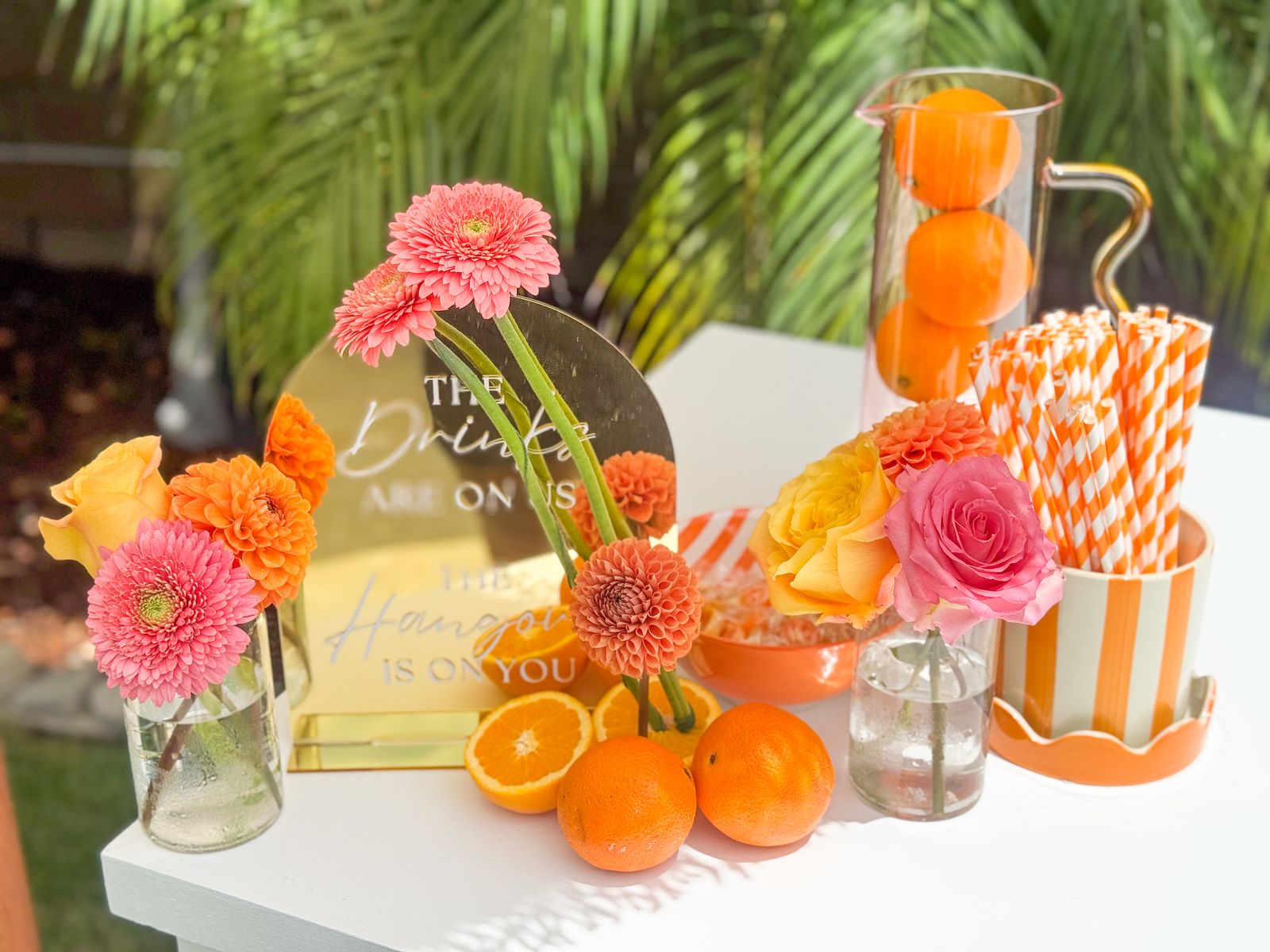 Pink and orange drinks table with fresh citrus and striped straws