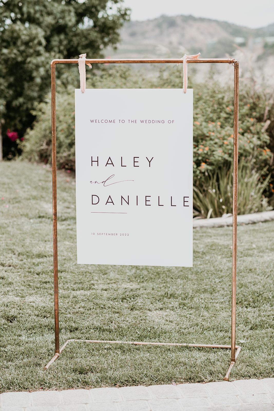 Ceremony welcome sign on a copper stand in a vineyard