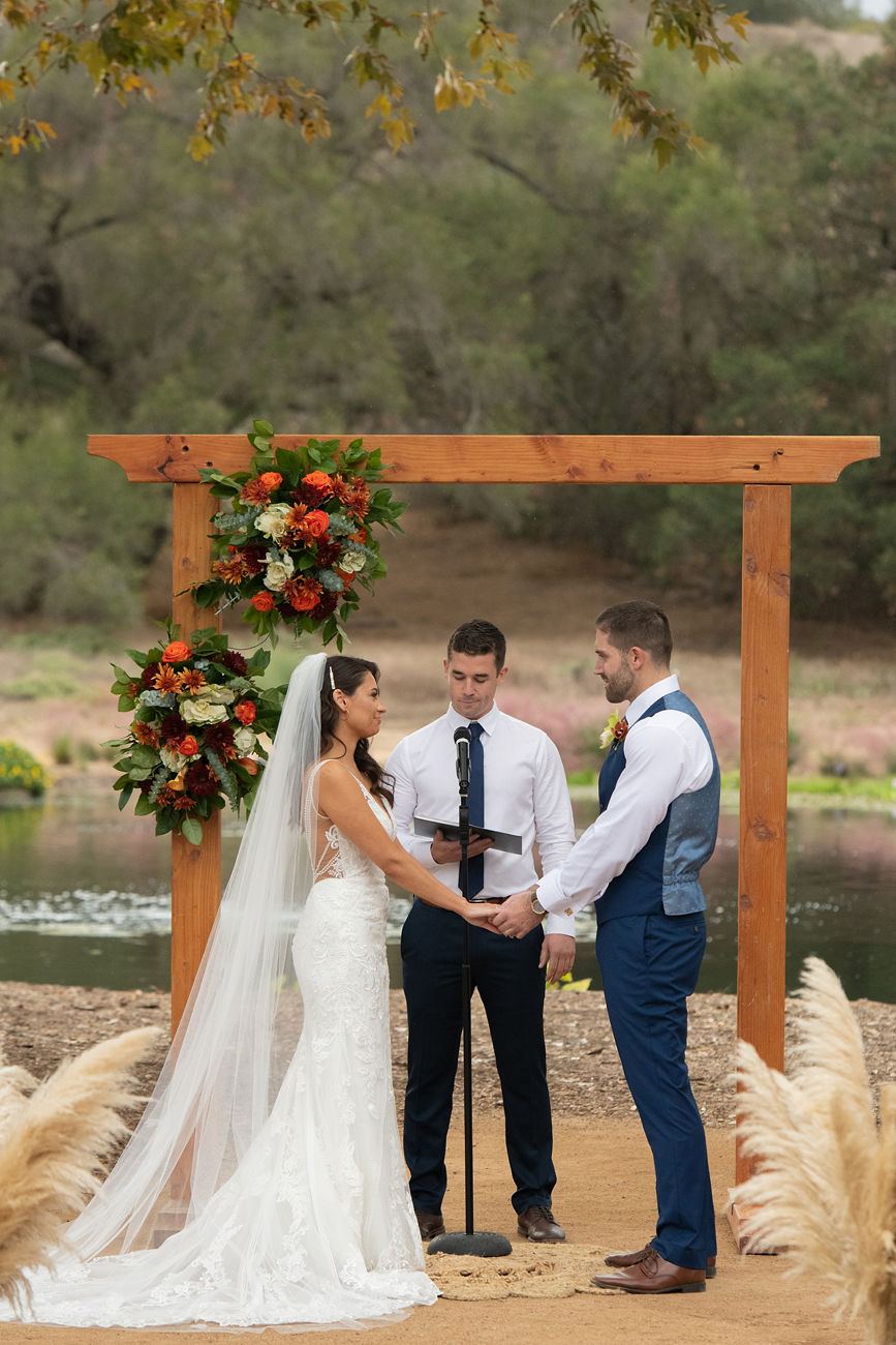 Vineyard ceremony under a wooden arch with florals