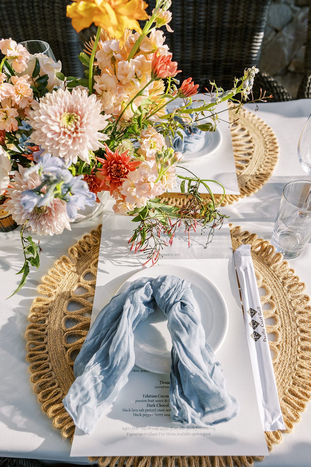 Blue and gold tablescape with woven chargers and dahlia centerpieces