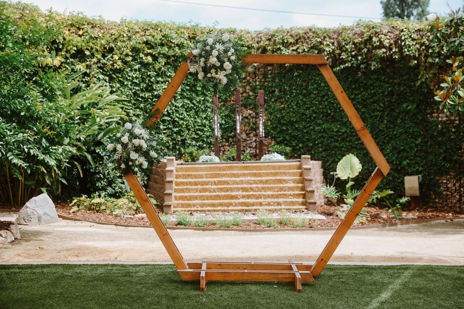 Hexagon wedding arch on a greenery wall backdrop