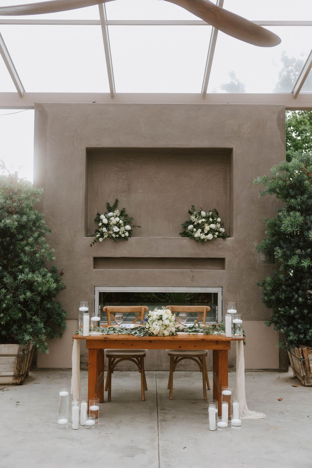 White floral arrangements across a fireplace mantel