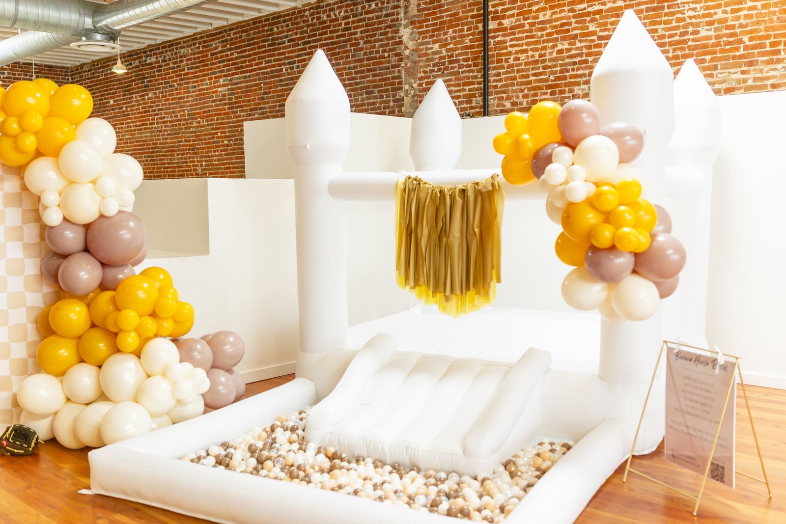White bounce castle dressed with a mustard and neutral garland
