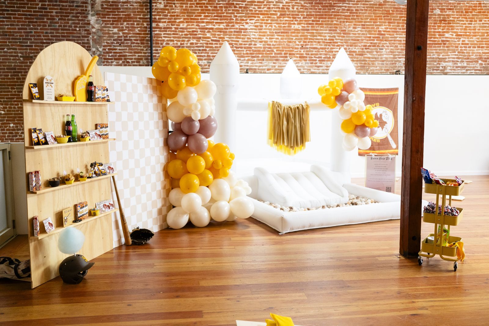 Baseball themed first birthday with a white bounce house and balloon garlands
