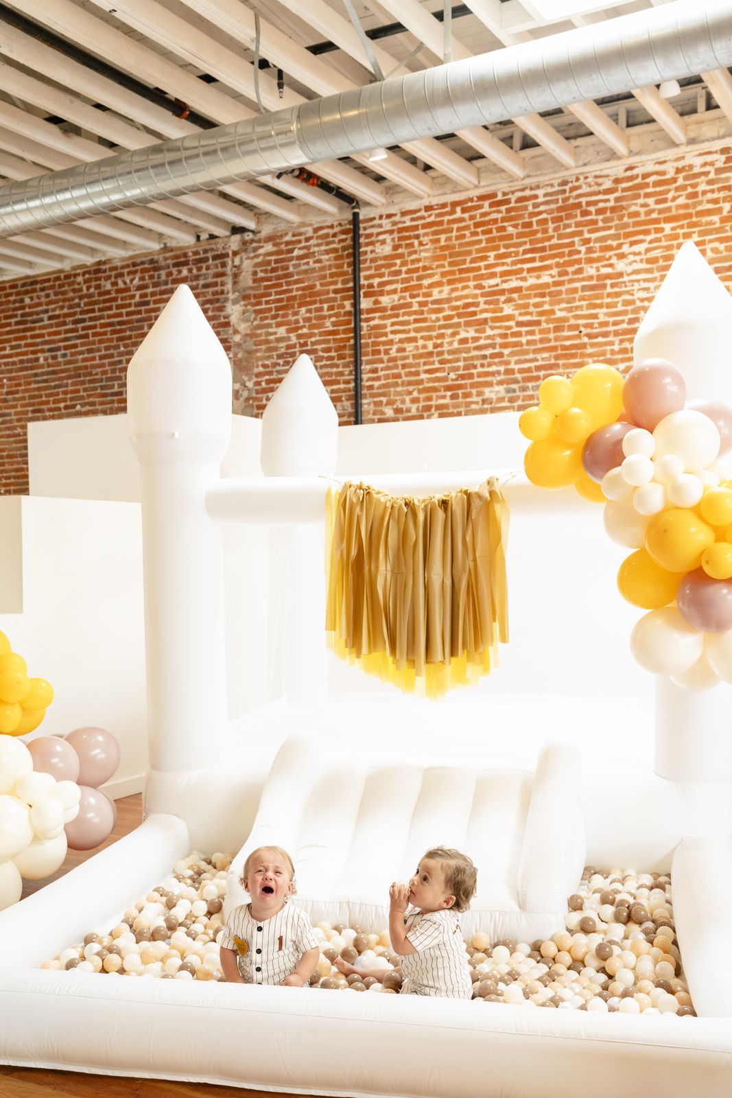 White bounce castle with a neutral ball pit at a first birthday
